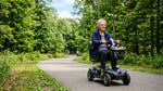 Senior riding a modern electric mobility scooter on a paved path in a Canadian park