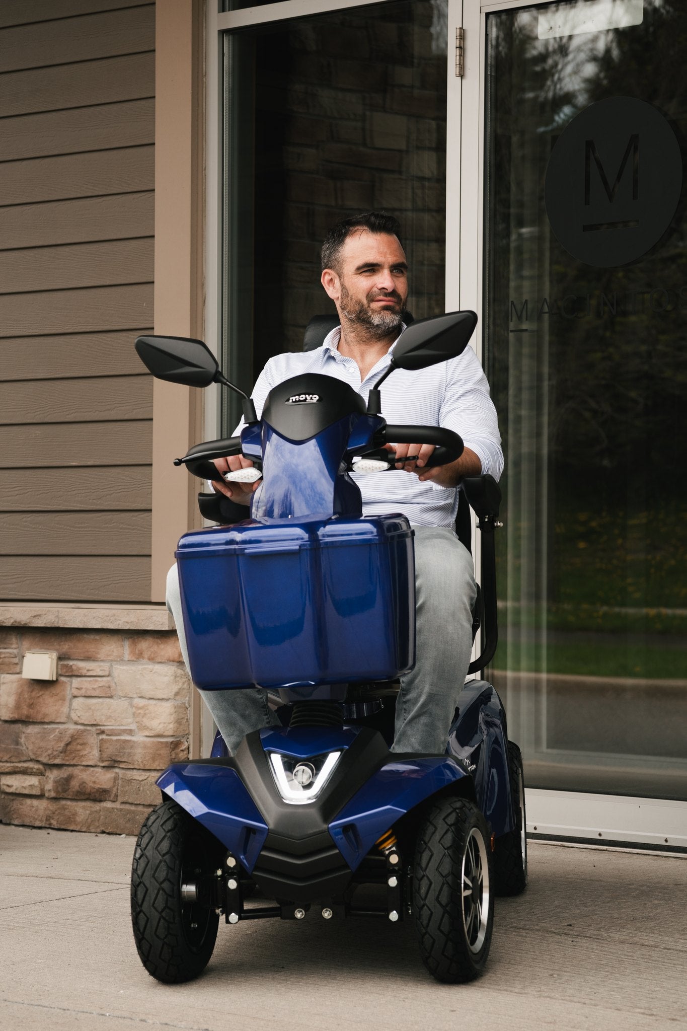 Man riding a blue Movo Sutton mobility scooter outside a building
