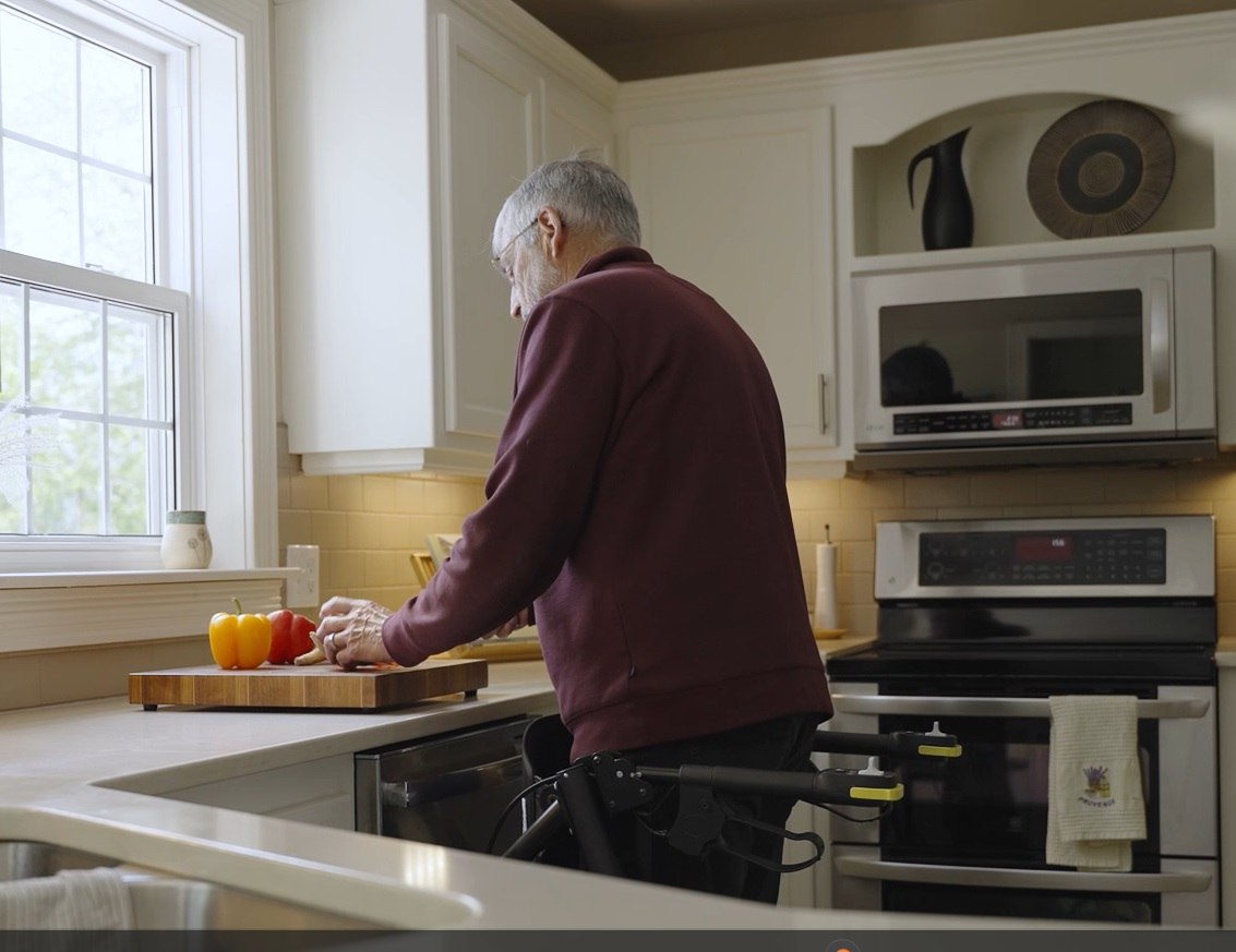 RAYMEX Lift Quattro used as a standing aid at a kitchen counter while preparing food